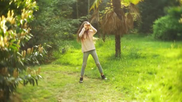 4K. menina elegante com cabelo longo dançando dança moderna em um parque da cidade . — Vídeo de Stock