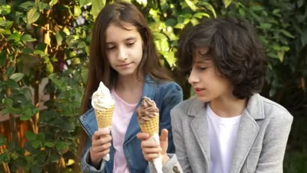 Adolescentes lindos, chico y chica comiendo helado en el parque y hablando. 4k — Vídeos de Stock