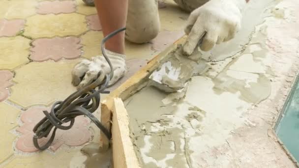 Spatule et seau avec mortier sur le chantier. le constructeur termine la surface avec du plâtre. 4k. réparation de piscine . — Video