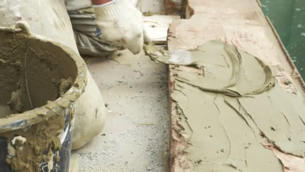 Spatel en emmer met mortel op de bouwplaats. de bouwer eindigt het oppervlak met pleister. 4k. — Stockvideo