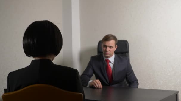Ένας άνθρωπος σε ένα κοστούμι θέτει ερωτήματα σε μια μελαχρινή γυναίκα σε μια συνέντευξη. 4 k. συνέντευξη. προσλήψεις — Αρχείο Βίντεο