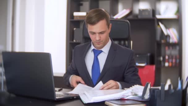 Un homme finit de travailler dans le bureau avec des documents et un ordinateur portable. 4k. fin de journée — Video