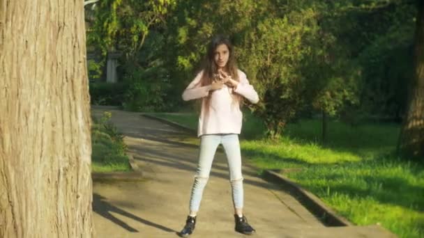 4k. стильная девушка с длинными волосами танцует современный танец в городском парке . — стоковое видео