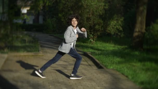 4K. bonito elegante menino adolescente dançando em um parque da cidade . — Vídeo de Stock