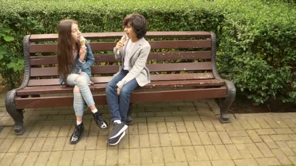Niedliche Teenager, Jungen und Mädchen, die im Park Eis essen und miteinander reden. 4k — Stockvideo