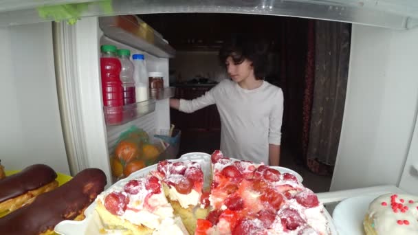 Niño comiendo frente al refrigerador en medio de la noche. 4k — Vídeos de Stock