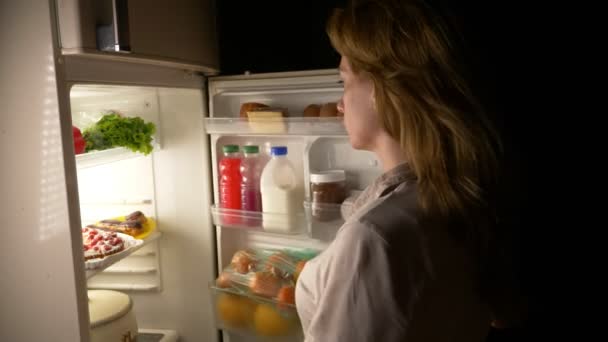 La mujer abre el refrigerador por la noche. hambre nocturna. dieta. gula, 4k — Vídeo de stock