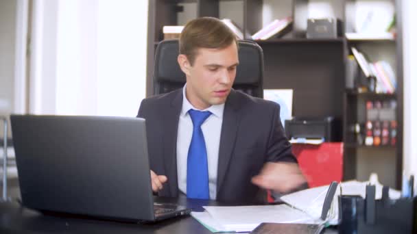 Un homme d'affaires qui scanne des documents, fronce les sourcils, à l'aide d'un ordinateur portable, n'effectue pas une tâche urgente dans le bureau, il n'y a pas assez de temps, 4k — Video