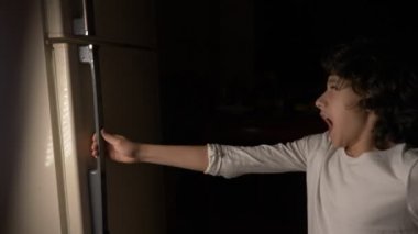 Gece yarısı buzdolabının önünde yeme çocuk. 4k