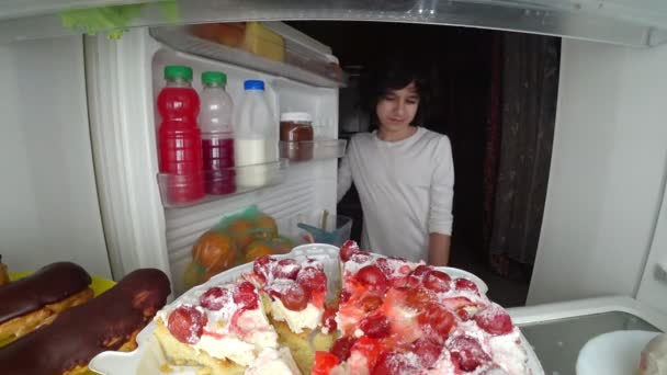 Niño comiendo frente al refrigerador en medio de la noche. 4k — Vídeo de stock