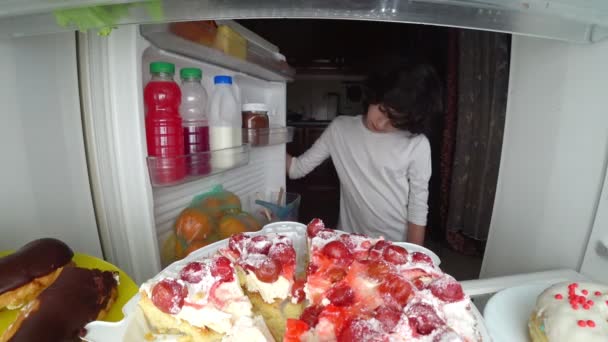 Το παιδί τρώει μπροστά από το ψυγείο στη μέση της νύχτας. 4k — Αρχείο Βίντεο