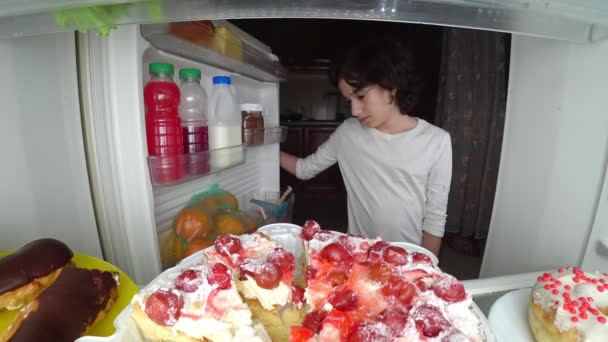 Niño comiendo frente al refrigerador en medio de la noche. 4k — Vídeo de stock