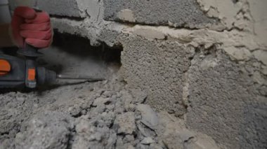 bir inşaat alanında, bir işçi bir perforator duvara vurma. 4k