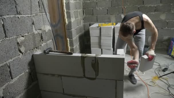 En byggeplads, en bygherre sætter en mur af gasblokke. 4k . – Stock-video