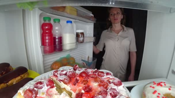 Žena otevírá lednici v noci. Noční hlad. strava. obžerství, 4k — Stock video
