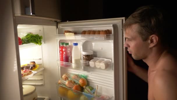 Młody człowiek mięśni otwiera lodówkę w nocy. nocny głód. diety. obżarstwo, 4k — Wideo stockowe