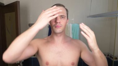Yakışıklı bir adam bir yüz banyoda ayna önünde bir krem ile smear. 4k