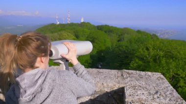 kadın sarışın gezgin bir dağın tepesinde bir teleskop aracılığıyla arıyor. 4k, ağır çekim