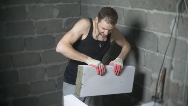 Auf einer Baustelle stellt ein Bauarbeiter eine Wand aus Gasblöcken auf. 4k. — Stockvideo