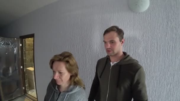 Nuevos colonos, una pareja de casados visitan un nuevo apartamento, evaluar los trabajos de reparación del apartamento. son felices. 4k — Vídeo de stock