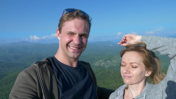 Una pareja, un hombre y una mujer hacen un sefi con vistas a las montañas magníficas. 4 k. Disparos en cámara lenta — Vídeos de Stock