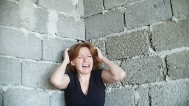 Mujer infeliz desesperada junto a la pared. 4k, el concepto de estrés y desesperación — Vídeo de stock