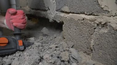 bir inşaat alanında, bir işçi bir perforator duvara vurma. 4k