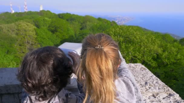 Kvinna blondin och hennes son teenager, resenärer, tittar genom ett teleskop på toppen av ett berg. 4k, Slowmotion — Stockvideo