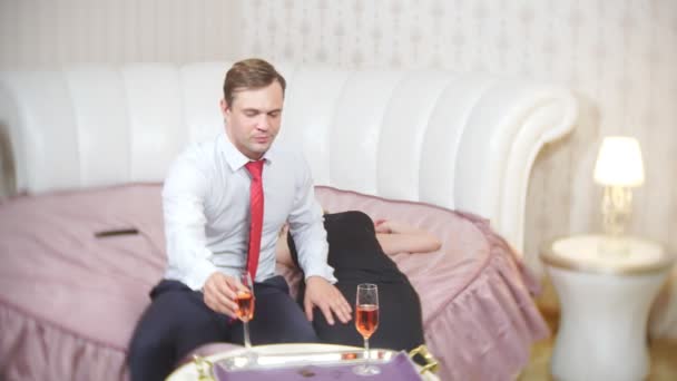 Een opgewonden nadenkende man zit op het bed voelt triest en ongerust, een peinzende man kijkt naar een dronken slapende meisje, teleurstelling met seksuele problemen, 4k — Stockvideo