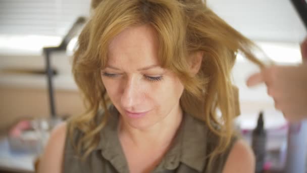 Saç stilisti bir kıvırcık saç şekillendirme kullanan bir kız için yapar. Kuaför iş başında. 4k — Stok video