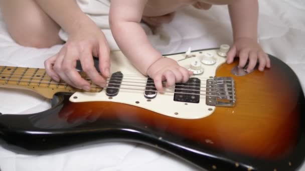 Ein kleiner Junge und seine Mutter spielen E-Gitarre. Nahaufnahme der Hände — Stockvideo