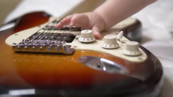 Malý batole si hraje s elektrickou kytarou. detailní záběr
