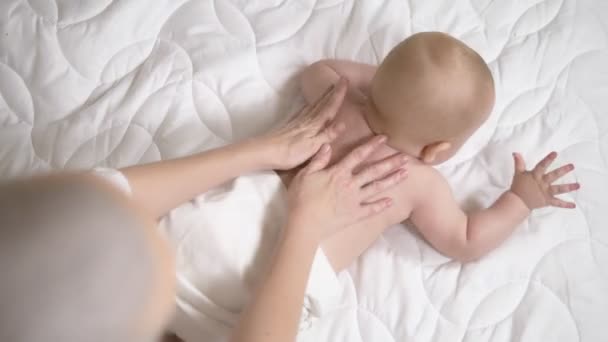 Жіночі руки масажують дитину в ліжку. крупним планом — стокове відео