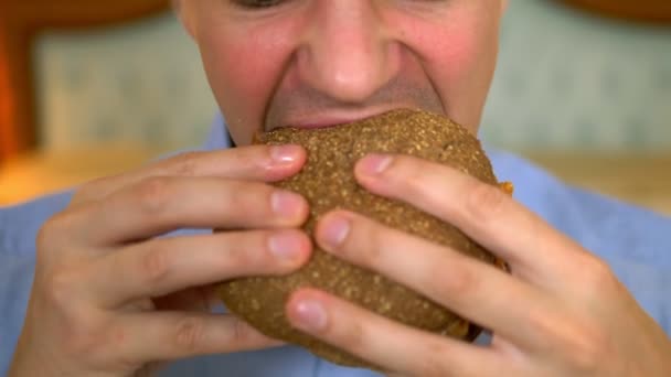 Primer plano. Hombre de negocios guapo está comiendo comida rápida sentado en la cama en un interior de lujo . — Vídeos de Stock