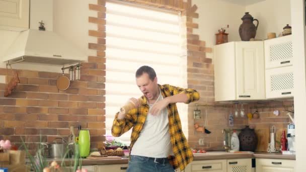 Счастливый молодой человек, танцующий на кухне. Песни поёт — стоковое видео