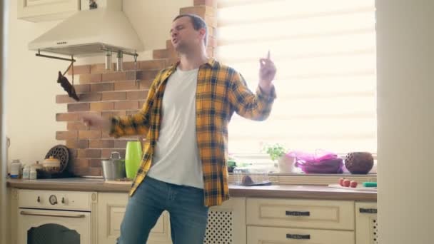 Fröhlicher junger Mann tanzt in der Küche. singt Lieder — Stockvideo