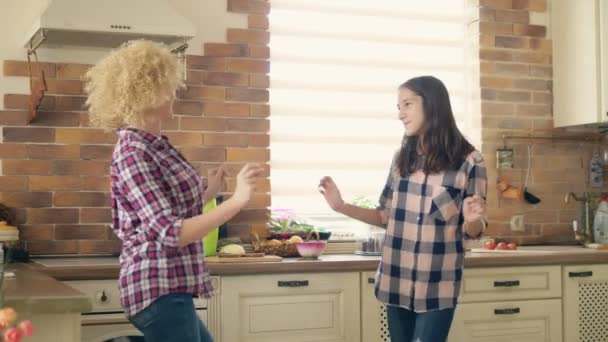 Dancing with mom. Cute teen daughter dancing in the kitchen with her loving mother — Stock Video