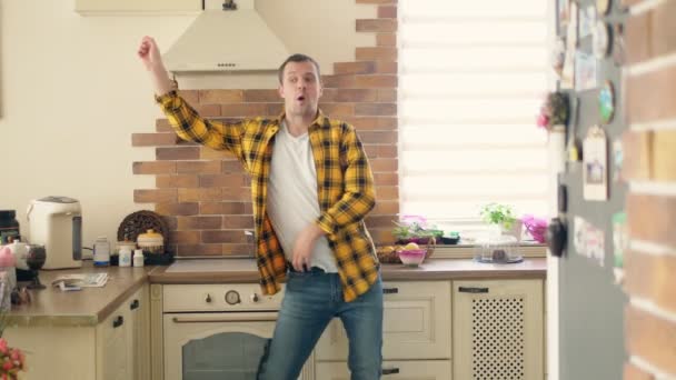 Όμορφος αστείος άντρας χορεύει στην κουζίνα στο σπίτι και διασκεδάζει. — Αρχείο Βίντεο