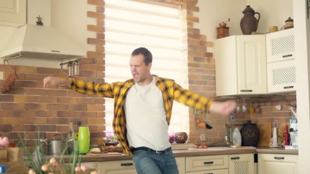 Knappe grappige man dansen in de keuken thuis en plezier hebben — Stockvideo