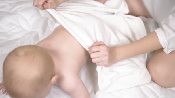 Женские руки массируют ребенка в постели. макро — стоковое видео