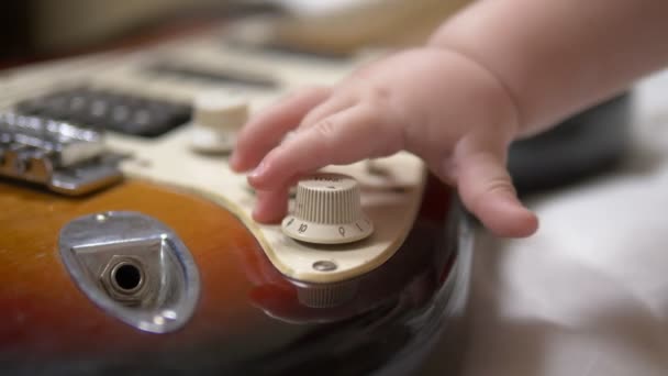 Mały chłopczyk bawiący się gitarą elektryczną. ręce zbliżenie — Wideo stockowe