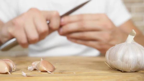 Testa di aglio primo piano, mani maschili sbucciare l'aglio su una tavola di legno — Foto Stock
