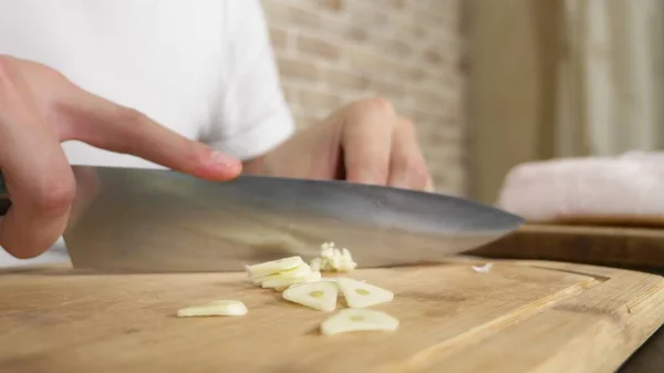 Mani maschili tagliano l'aglio su una tavola di legno. primo piano — Foto Stock