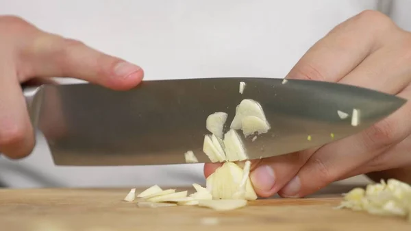 Mani maschili tagliano l'aglio su una tavola di legno. primo piano — Foto Stock