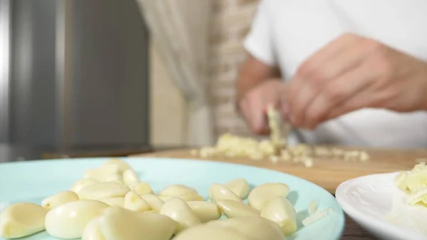 Mani maschili tagliano l'aglio su una tavola di legno. primo piano — Foto Stock