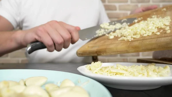 Male hands cut garlic on a wooden board. close-up — Stock Photo, Image