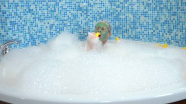 Yüzünde yeşil kozmetik maskesi olan ve duş bonesi takmış köpükle banyo yapan ve sarı oyuncak ördekle oynayan genç bir adam. Tuhaf insanların mizah anlayışı, maceraları..