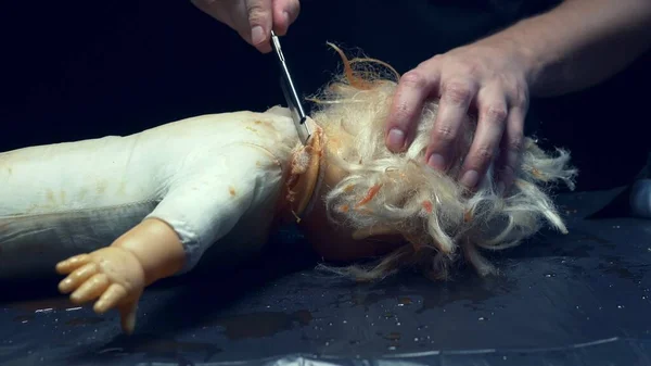 Mãos masculinas viu uma cabeça de bonecas assustadora, halloween — Fotografia de Stock