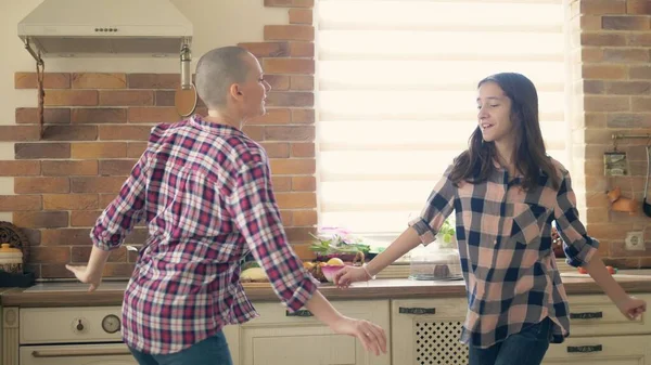 Dancing with mom. Pretty teenage daughter dancing in the kitchen with her loving bald mother — ストック写真