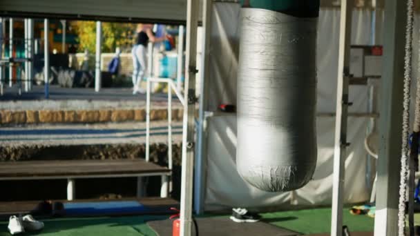 Blurred background. concept of outdoor playground on the street. in focus a punching punching bag, in the background blurry people are engaged in open air — Stock Video